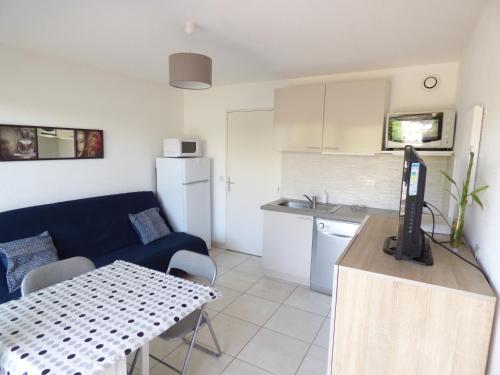 un salon avec un canapé bleu et une cuisine dans l'établissement T2 cabine Cosy, à Palavas-les-Flots