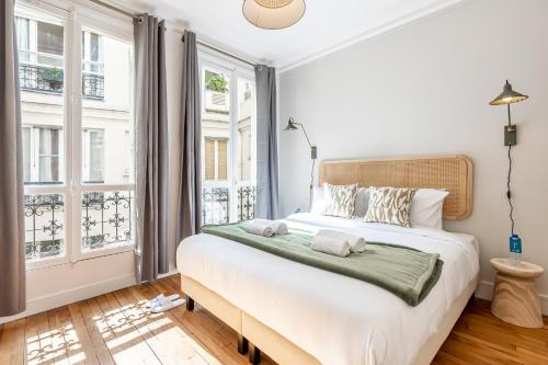 une chambre avec un grand lit et deux fenêtres dans l'établissement Sweett - Maison Wagram, à Paris