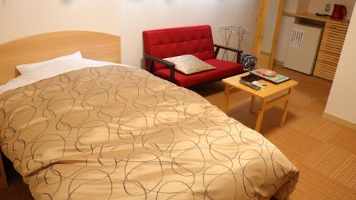 a bedroom with a bed and a red chair at Ashinomaki Grand Hotel in Aizuwakamatsu