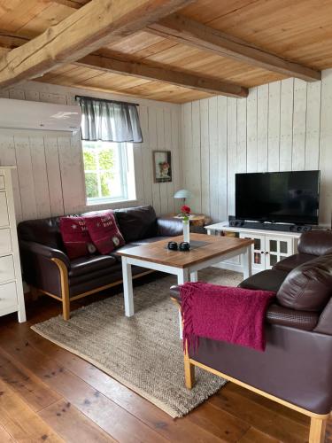 ein Wohnzimmer mit einem Sofa und einem Tisch in der Unterkunft Fogdarps B&B -Eget gästhus- in Förslöv