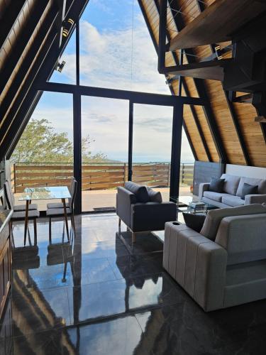 a living room with couches and a table and windows at Wind Houses, Casas de Viento in Monteverde Costa Rica