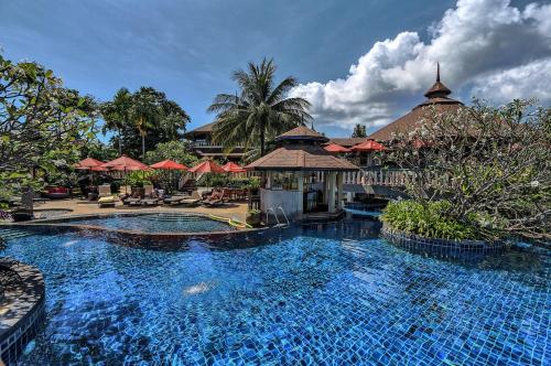 a pool at a resort with umbrellas at Mangosteen Ayurveda & Wellness Resort - SHA Plus in Rawai Beach