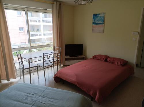 拉羅歇爾的住宿－T1 confortable situé 100m plage des Minimes，一间卧室配有一张床和一张桌子及一台电视