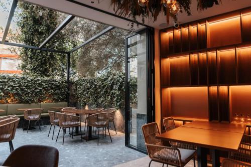 a restaurant with wooden tables and chairs and glass walls at Boutique Hotel OLOM - Adults recommended in Cádiz