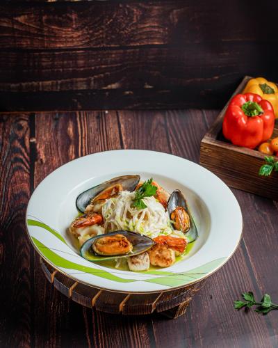 a plate of food with mussels and noodles on a table at Holiday Inn Dhaka City Centre by IHG in Dhaka