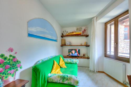 a green couch in a living room with a window at Il Nido dell'Artista - Happy Rentals in Tenno