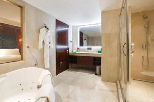 a bathroom with a tub and a sink and a mirror at Holiday Inn Dhaka City Centre by IHG in Dhaka