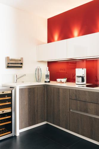 a kitchen with wooden cabinets and red walls at Consulat des Weins in Sankt Martin