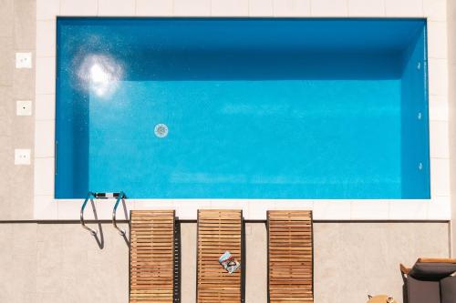 Una piscina con cuatro sillas marrones y un tanque azul. en Villa LA ZE, en Rogoznica