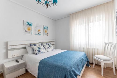 a white bedroom with a bed and a chair at Amplio y Luminoso en Leioa in Leioa