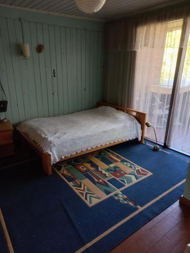 een slaapkamer met een bed op een blauw tapijt bij Engures māja - mežs un jūra in Engure