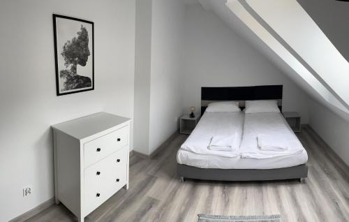 a white bedroom with a bed and a white dresser at Apartamenty i Pokoje DIMAN in Mrągowo