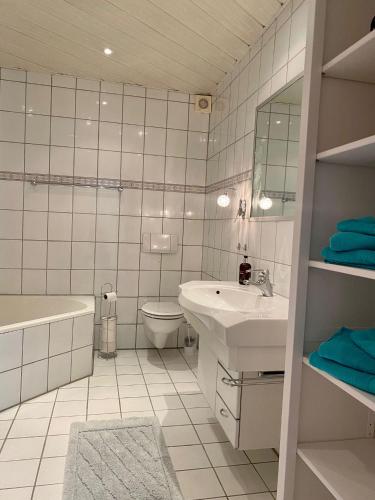 a bathroom with a sink and a tub and a toilet at Feriendomizil Mühlenblick in Xanten