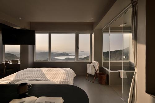 a bedroom with a bed and a large window at Daybreak in Jiufen