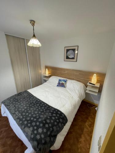 Un dormitorio con una cama con una manta blanca y negra. en Les Thermes 25 Le Mont Dore, en Le Mont-Dore