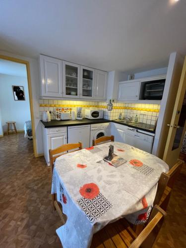 - une cuisine avec une table, une table et des chaises dans l'établissement Les Thermes 25 Le Mont Dore, à Le Mont-Dore
