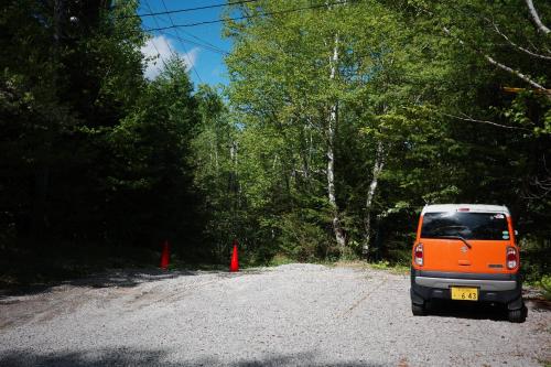 an orange van parked on a gravel road with trees at Raicho Onsen Inn in Matsumoto