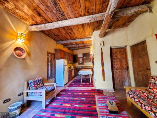 a living room with a wooden ceiling and a kitchen at Paloma Lodge in Siwa