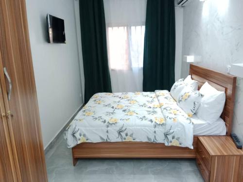 a bedroom with a bed with a white comforter at Studio Emeraude - cosy et climatisé - Résidence Saraba Mermoz in Dakar