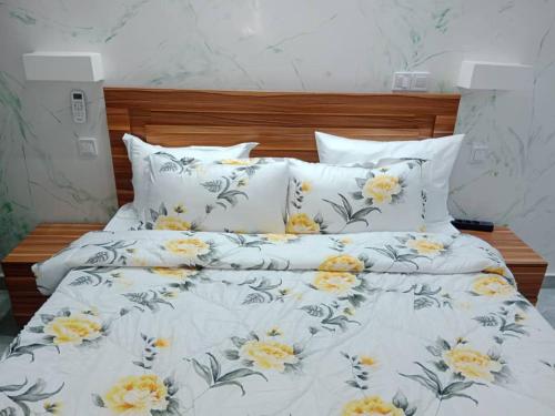 Una cama con sábanas blancas y flores amarillas. en Studio Emeraude - cosy et climatisé - Résidence Saraba Mermoz en Dakar