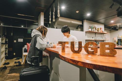 小樽的住宿－Tug-B Bar & Hostel，几个人站在一个有通道的柜台上
