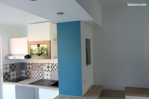 una cocina con armarios blancos y una columna azul en Studio, jardin, clim & parking, en Saint-Cyr-sur-Mer