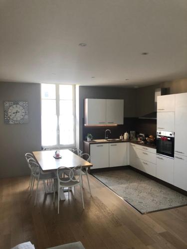 une cuisine avec des armoires blanches et une table et des chaises dans l'établissement Jardin des Plantes, au Mans