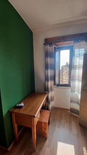 a room with a wooden table and a green wall at B&B Le Vie del Borgo in Castiglione di Sicilia