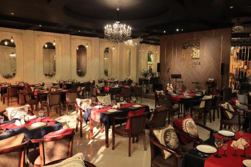 a restaurant with tables and chairs and a chandelier at Euro Asia Hotel in Samarkand