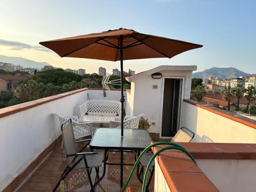 einen Tisch und Stühle auf einem Balkon mit Sonnenschirm in der Unterkunft Casa Rosina in Palermo