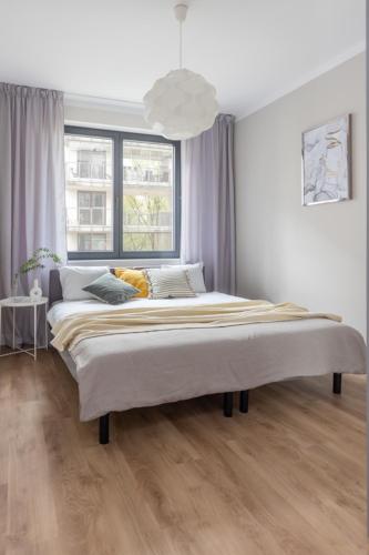 a large bed in a white room with a large window at Warsaw-Aparts Sokratesa in Warsaw