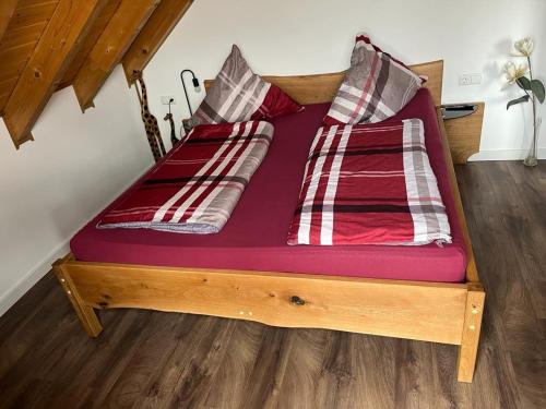 un letto in legno con due cuscini sopra di Ferienwohnung Geyer a Rennertshofen