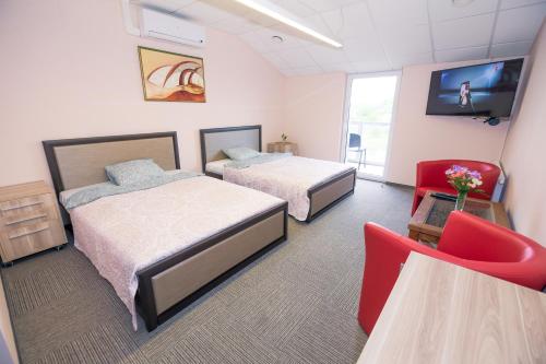 a hotel room with two beds and a tv at Rezidencija "Prieplauka" in Alytus