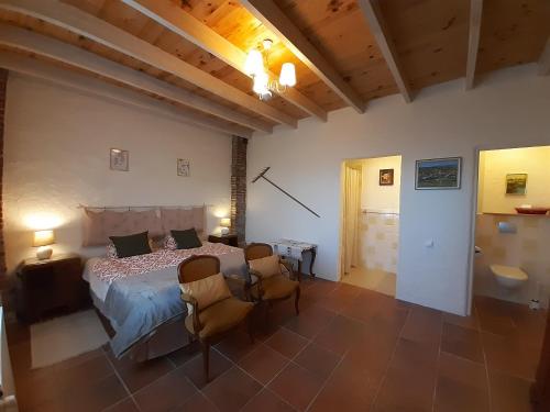 een slaapkamer met een bed en stoelen in een kamer bij BnB Ferme Beauregard Les Pyrénées in Artigat