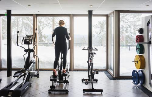 a woman looking out the window of a gym at Ski-Inn PyhäSuites in Pyhätunturi