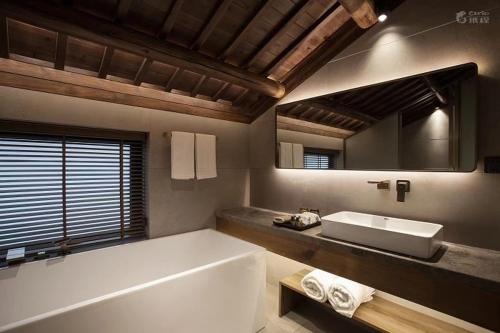 a bathroom with a tub and a sink and a mirror at Formeet Boutique Homestay in Hangzhou