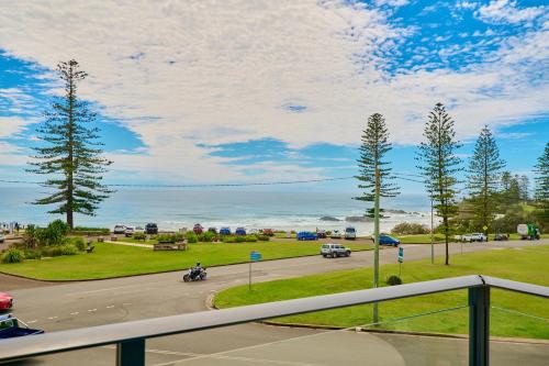 a view from a balcony of a road with trees and the ocean at ibis Styles Port Macquarie in Port Macquarie