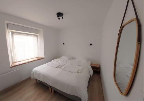 une chambre blanche avec un lit et un miroir dans l'établissement Le Cormoran emplacement idéal, moderne très équipé, à Thury-Harcourt