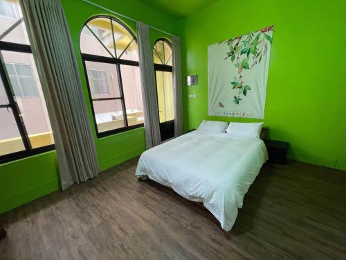 a green bedroom with a bed in a room with windows at Chunfa B&B in Huxi