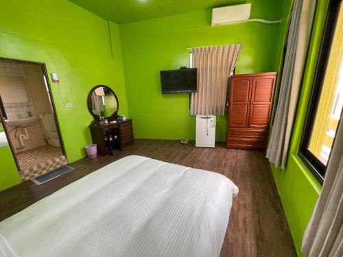a green bedroom with a bed and a mirror at Chunfa B&B in Huxi