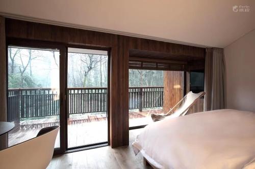 a bedroom with a bed and a balcony with sliding glass doors at Formeet Boutique Homestay in Hangzhou