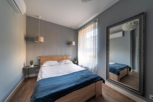 1 dormitorio con espejo grande y cama en ResiNest Apartamenty Kameralna Wesoła, en Białystok