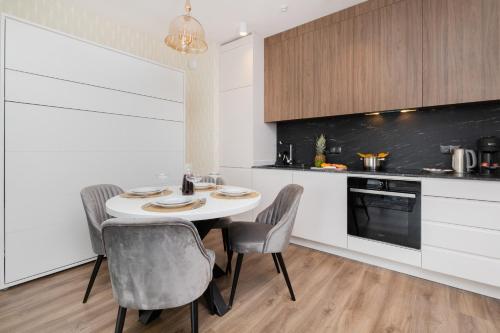 a kitchen with a white table and chairs in a room at Stunning Apartment with Parking in Gdansk Lower Town by Renters in Gdańsk