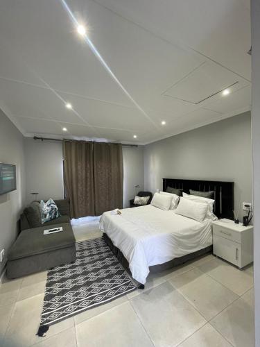 a bedroom with a large white bed and a couch at Clear Corner Suites in East London