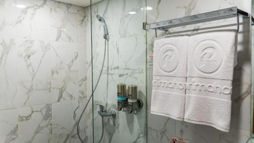 a shower in a bathroom with a glass shower door at d'primahotel Airport Jakarta Terminal 3 Wellness Center in Tangerang