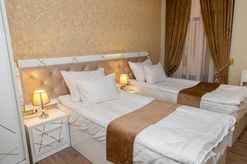 two beds in a hotel room with two lamps at The Royal Hotel in Samarkand