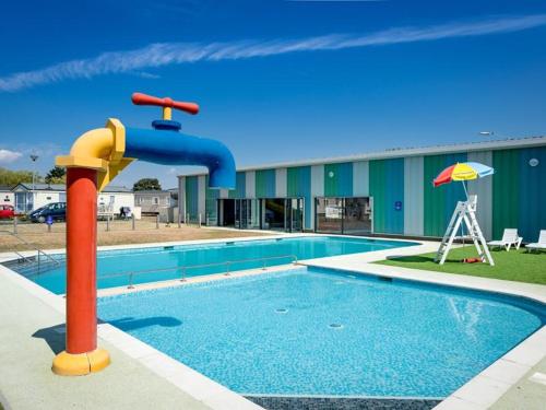 a pool with a water slide in front of a building at Seaside Holiday Home St. Osyth, Essex 2 Bathroom, 6 Berth with Country Views in Saint Osyth