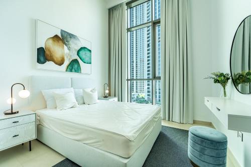a white bedroom with a large white bed and a window at Luxury StayCation - Fancy Apartment Connected To Burj Khalifa in Dubai