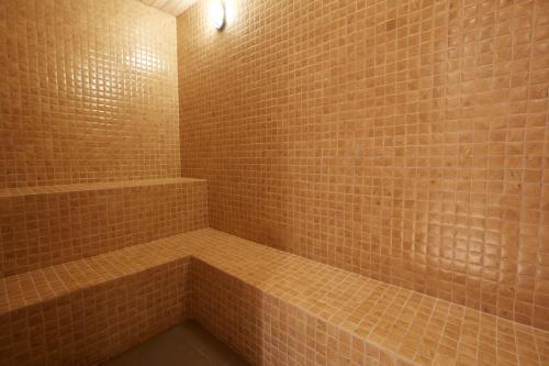 a bathroom with a shower with brown tile walls at Belmont Hotel Mactan in Mactan