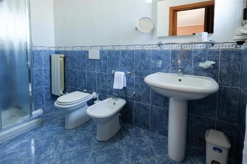 a blue tiled bathroom with a sink and a toilet at Bed&Belvedere in Otranto